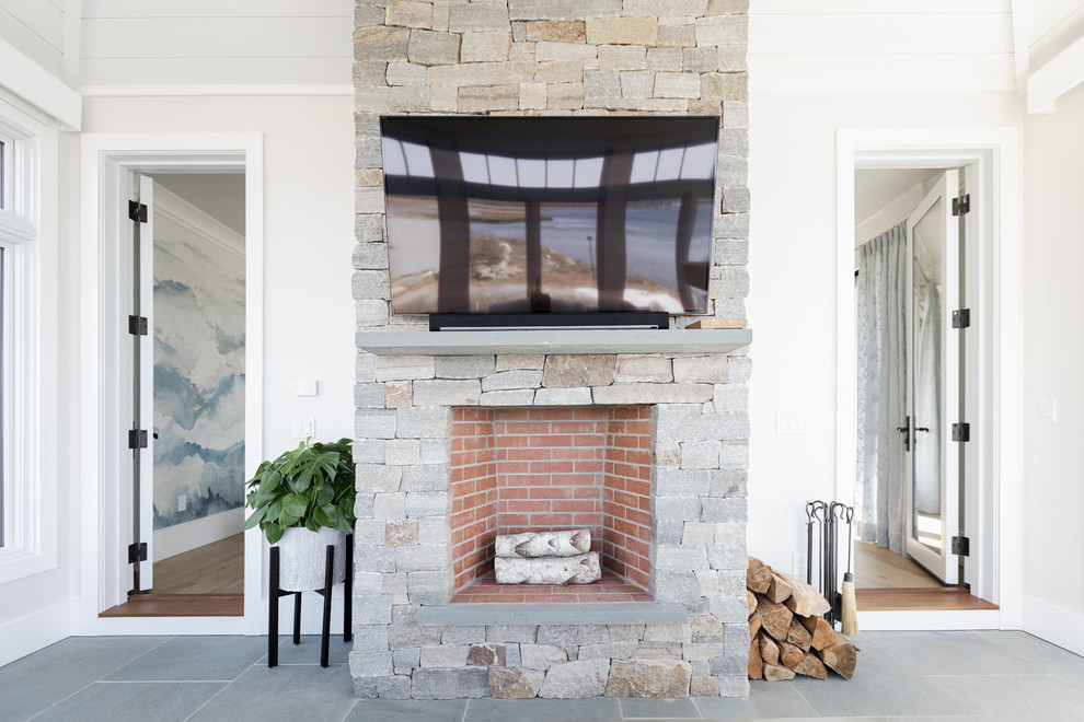 Large beach style gray floor and slate floor sunroom photo in Boston with a standard fireplace, a stone fireplace and a skylight