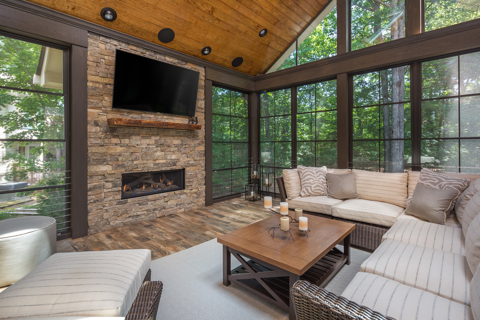 Inspiration for a large rustic conservatory in Raleigh with a ribbon fireplace, a stone fireplace surround, a standard ceiling, brown floors and a chimney breast.