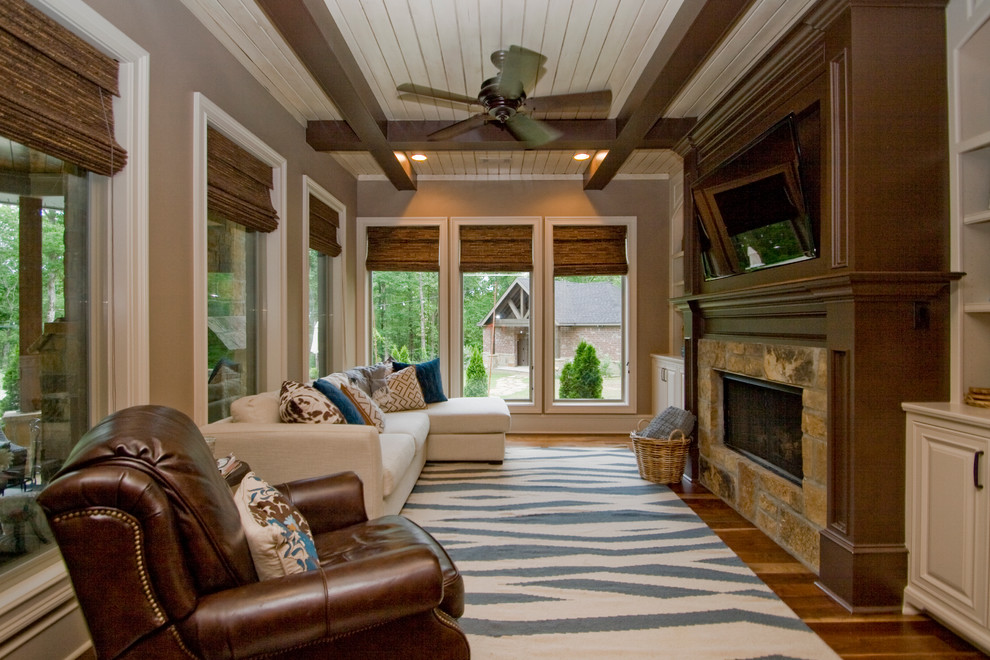 Immagine di una veranda rustica di medie dimensioni con pavimento in legno massello medio, camino classico, cornice del camino in pietra, soffitto classico e pavimento marrone