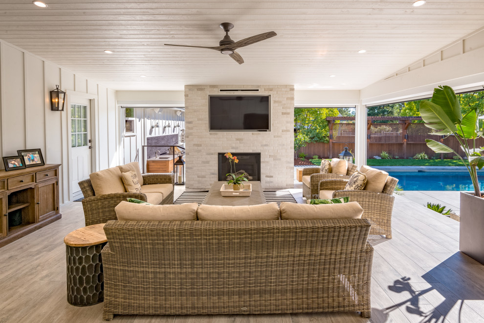 Photo of a large conservatory in San Francisco with medium hardwood flooring, a standard fireplace, a brick fireplace surround, a standard ceiling, brown floors and a chimney breast.