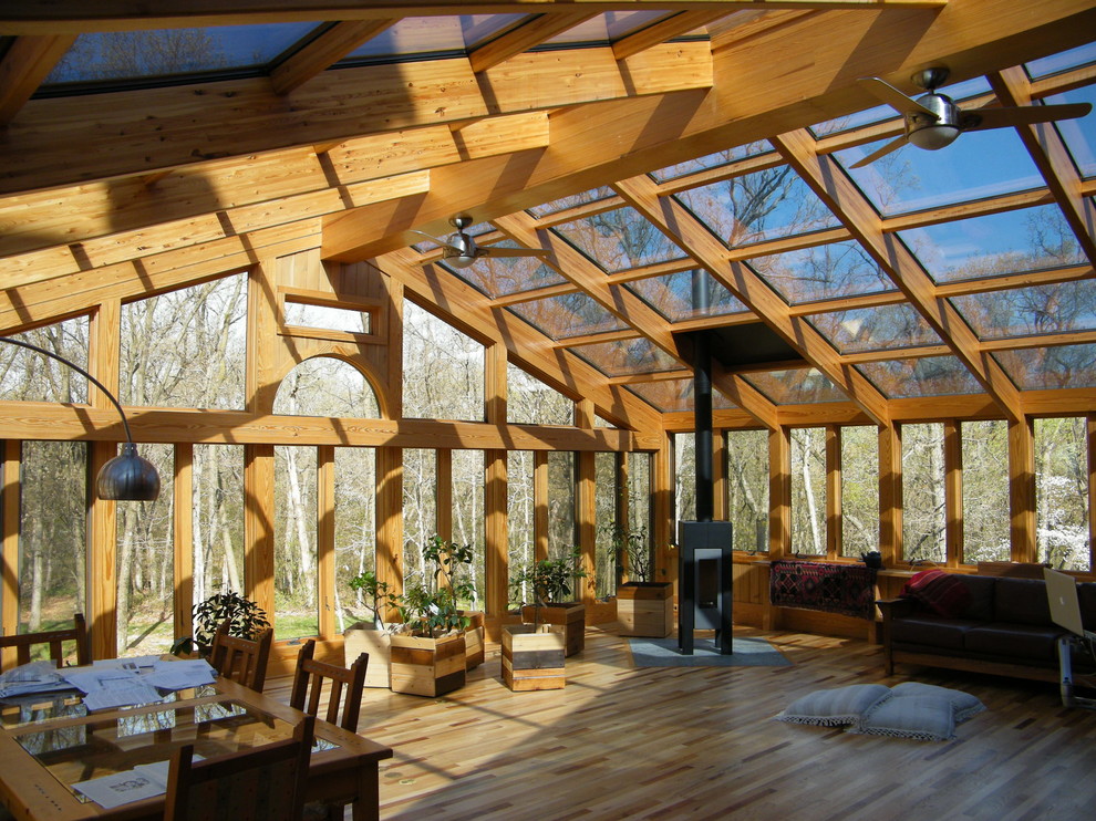 Immagine di una veranda con parquet chiaro, camino sospeso e soffitto in vetro