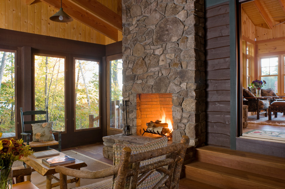 Inspiration pour une véranda traditionnelle de taille moyenne avec un sol en bois brun, un manteau de cheminée en pierre et une cheminée standard.