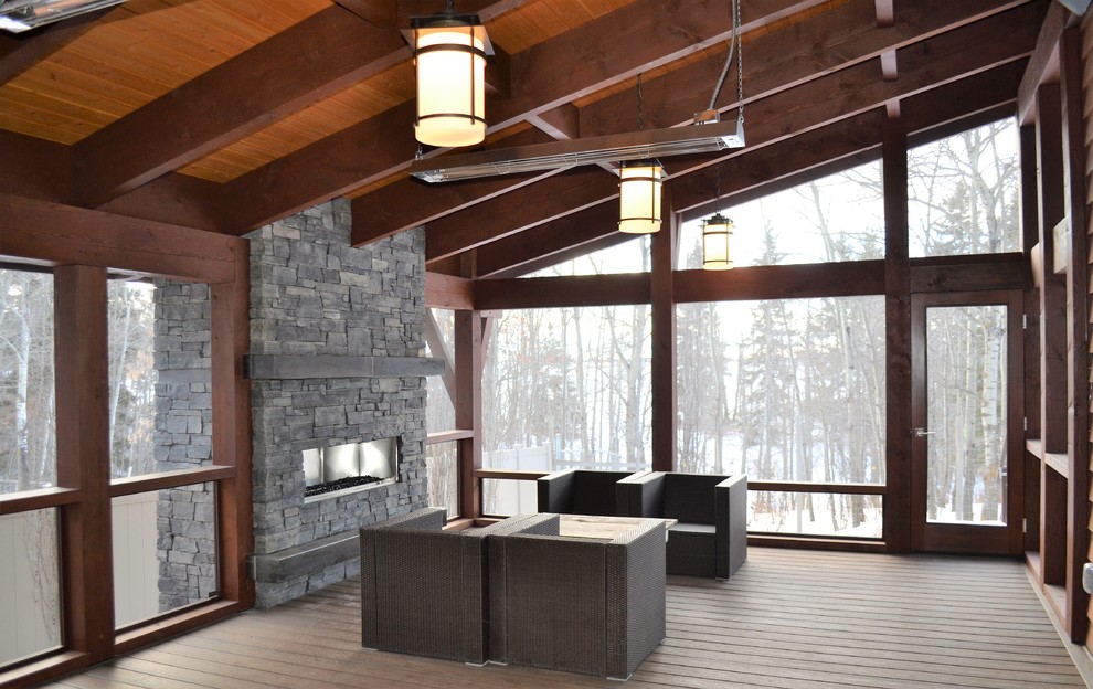 Exemple d'une grande véranda tendance avec une cheminée ribbon, un manteau de cheminée en pierre, un plafond standard, un sol marron et un sol en bois brun.