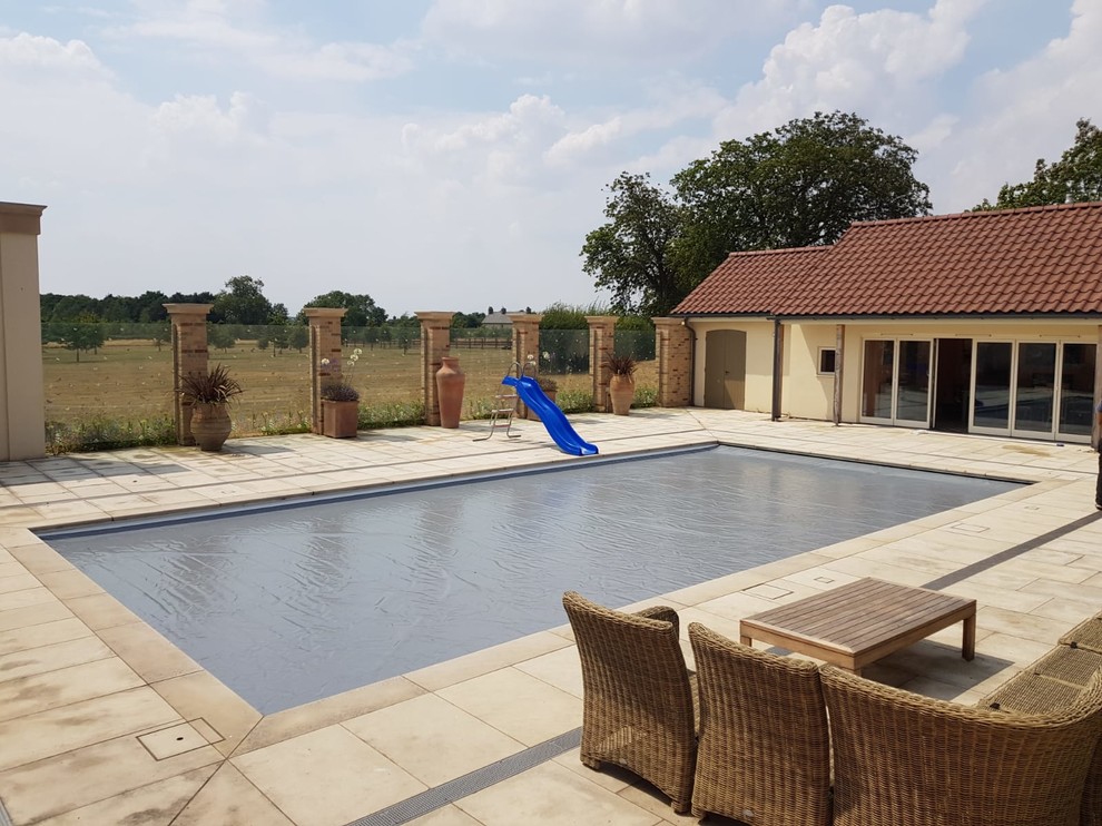 Rectangular swimming pool in Cambridgeshire with natural stone paving.