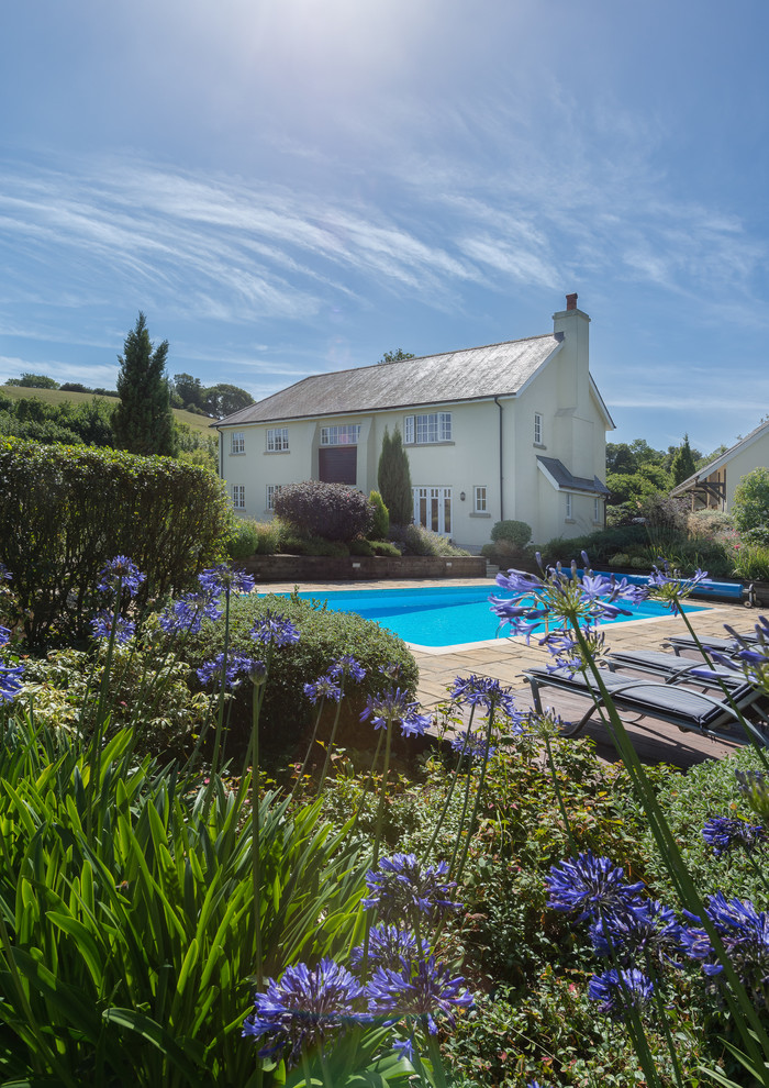 Foto de casa de la piscina y piscina de estilo de casa de campo grande rectangular en patio lateral con losas de hormigón