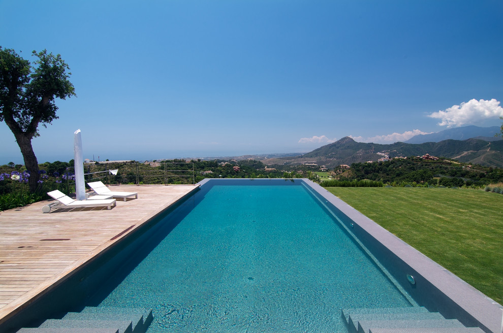 Diseño de casa de la piscina y piscina infinita actual grande rectangular en patio trasero con entablado