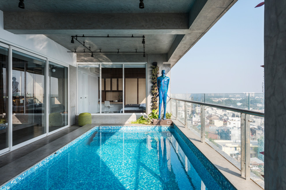 На фото: спортивный, прямоугольный бассейн в доме в стиле лофт с покрытием из бетонных плит с
