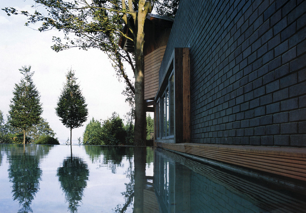 Inspiration for a huge contemporary courtyard concrete infinity pool fountain remodel in London