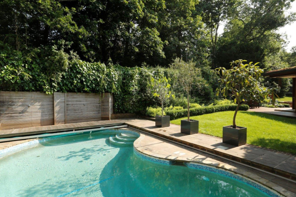Mittelgroßer Moderner Schwimmteich hinter dem Haus in Nierenform mit Natursteinplatten in London