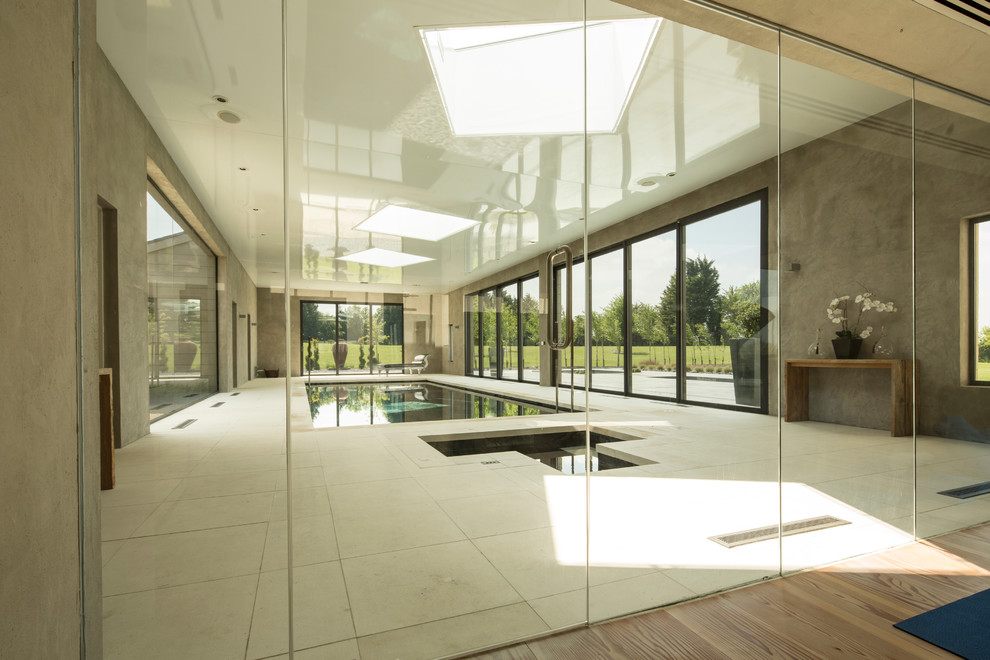 Ispirazione per una grande piscina coperta monocorsia minimalista rettangolare con una vasca idromassaggio e pavimentazioni in pietra naturale