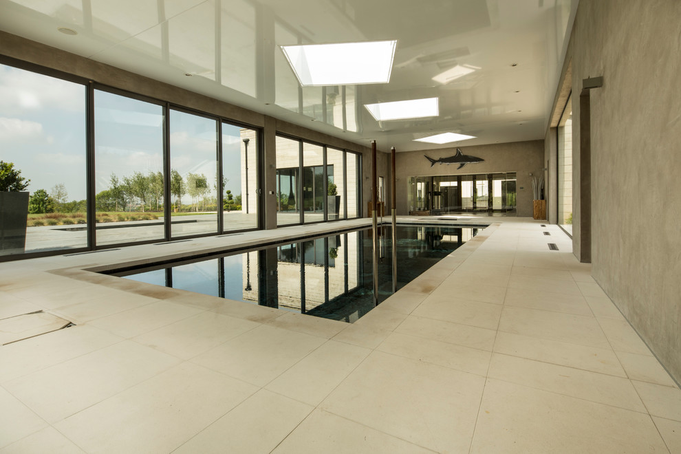 Immagine di una grande piscina coperta monocorsia moderna rettangolare con una dépendance a bordo piscina e pavimentazioni in pietra naturale