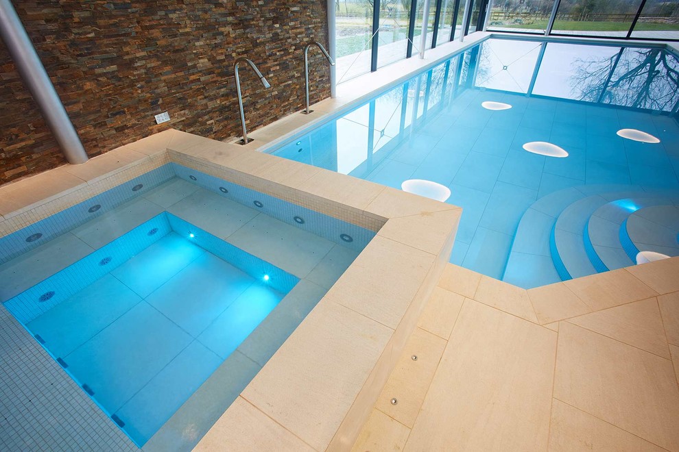 Пример оригинального дизайна: бассейн в форме фасоли в доме в современном стиле с джакузи и покрытием из каменной брусчатки