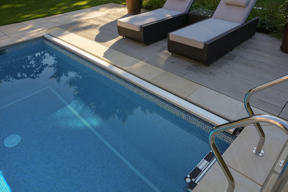Esempio di una grande piscina classica rettangolare dietro casa con piastrelle