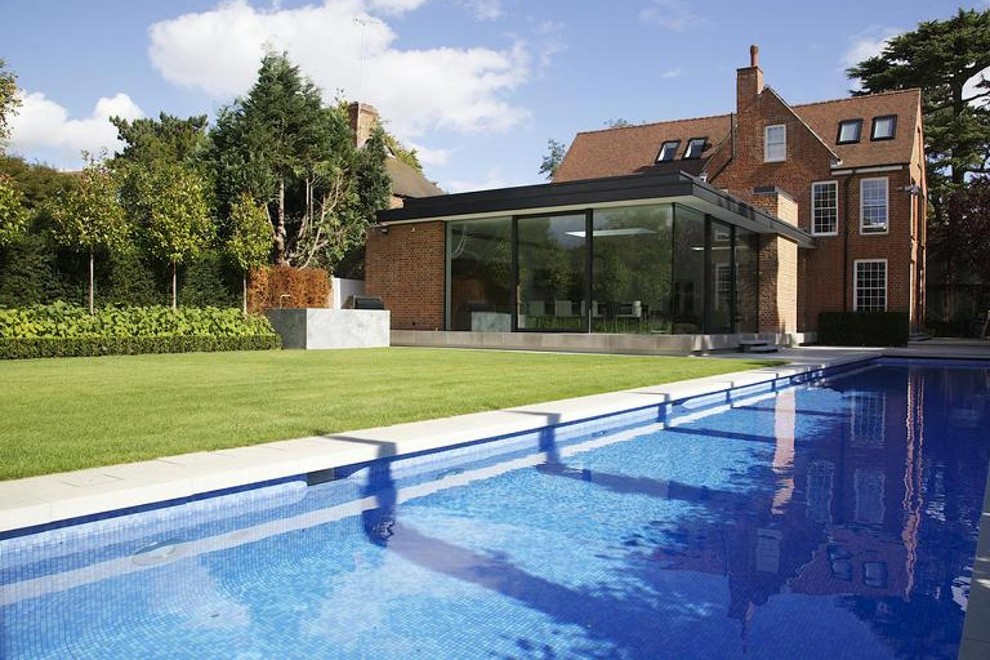 Foto de piscina actual rectangular en patio trasero con suelo de baldosas