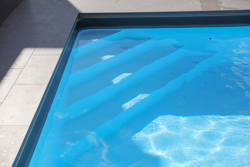 Cette image montre une piscine arrière minimaliste de taille moyenne et rectangle avec du carrelage.