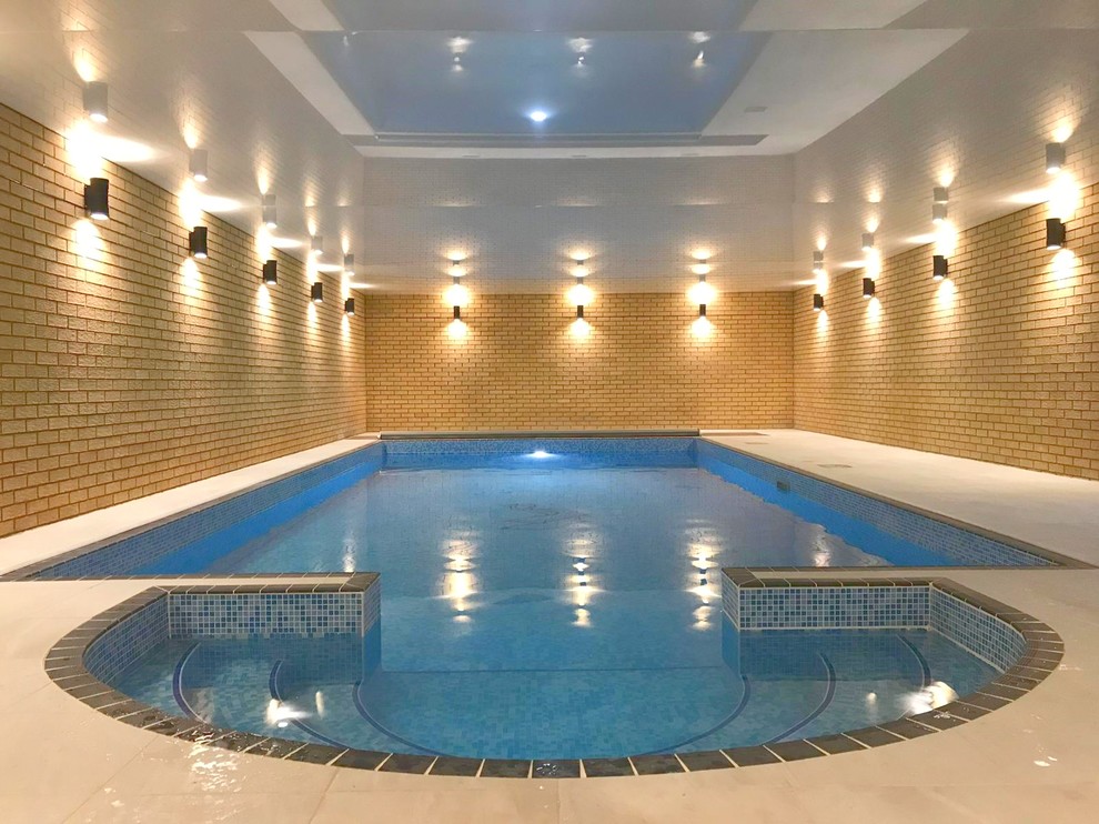 This is an example of a medium sized contemporary indoor rectangular swimming pool in Other with a pool house and natural stone paving.