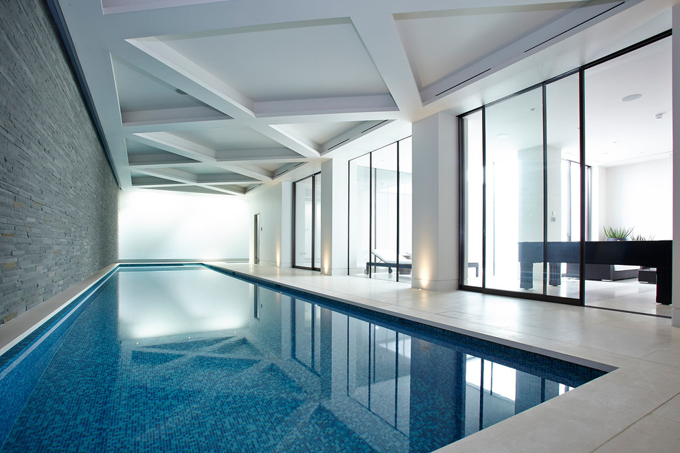 Imagen de piscina actual interior y rectangular con suelo de baldosas