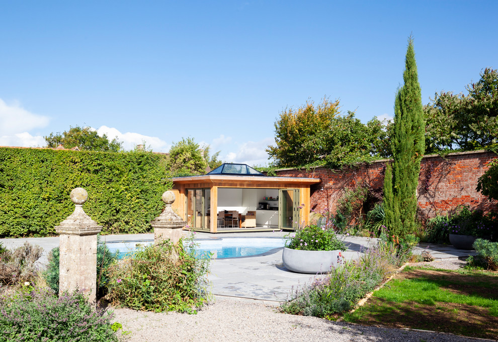 Design ideas for a medium sized contemporary back kidney-shaped above ground swimming pool in Wiltshire with a pool house and natural stone paving.
