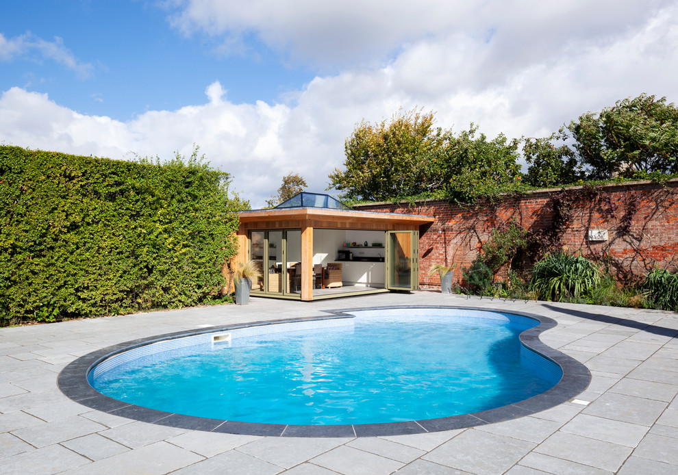 Ispirazione per una piscina fuori terra design a "C" di medie dimensioni e dietro casa con una dépendance a bordo piscina e pavimentazioni in pietra naturale