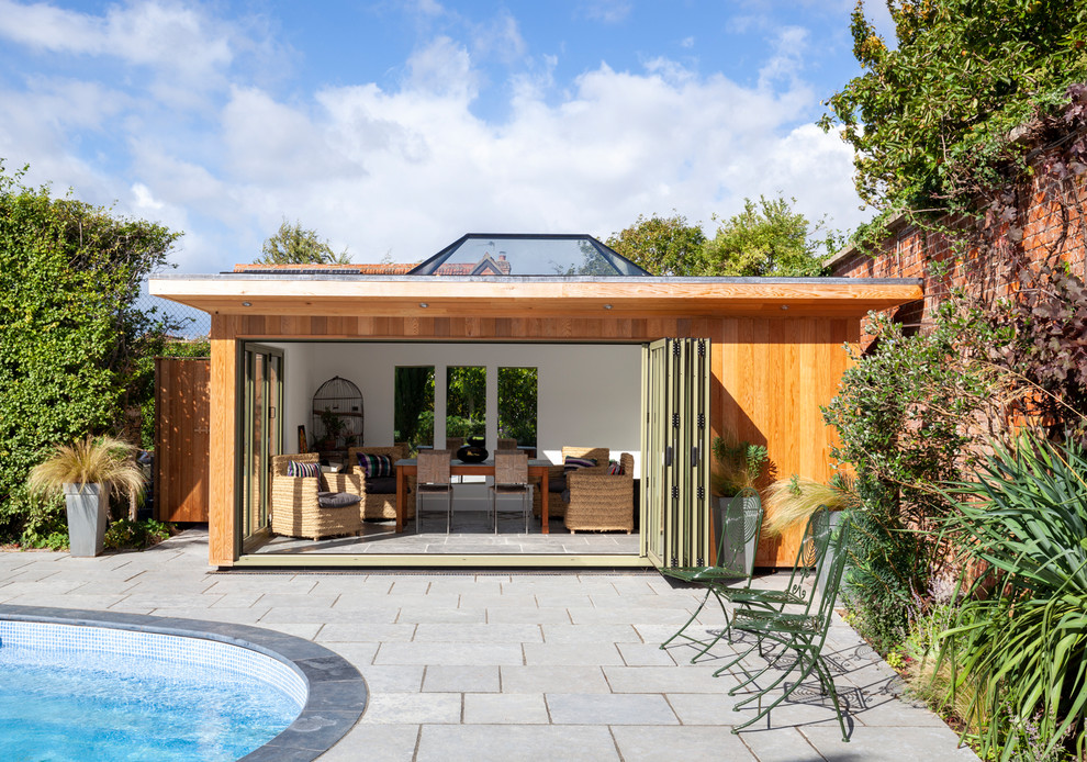 Foto de casa de la piscina y piscina actual de tamaño medio tipo riñón en patio trasero con adoquines de piedra natural