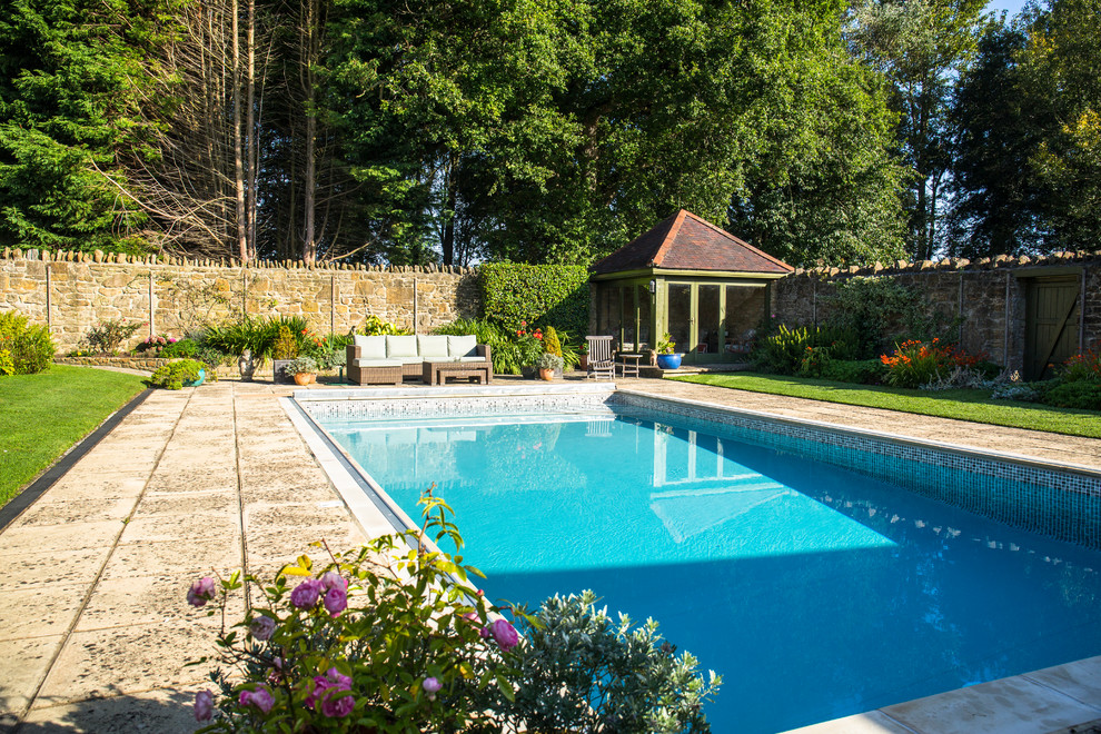 This is an example of a large classic back rectangular lengths swimming pool in Dorset with natural stone paving.