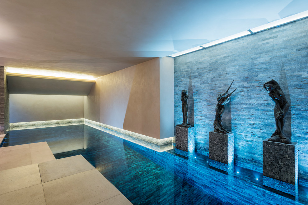 Esempio di una piscina coperta minimalista di medie dimensioni con fontane e lastre di cemento