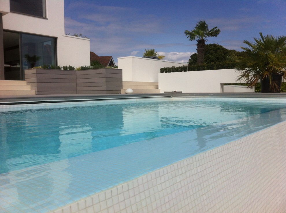 Пример оригинального дизайна: большой прямоугольный бассейн-инфинити на переднем дворе в морском стиле с домиком у бассейна и настилом