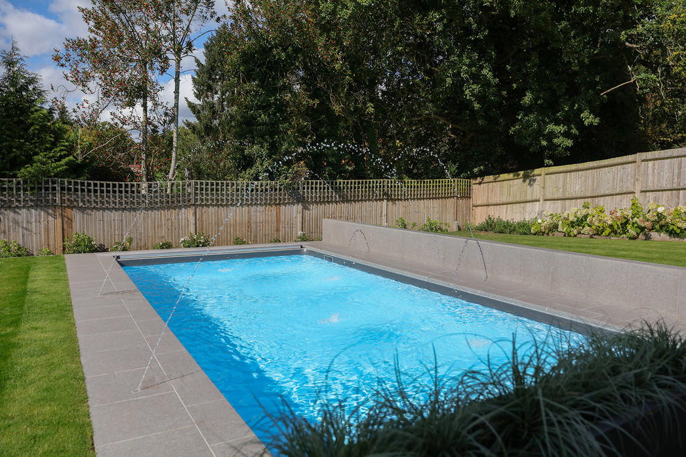This is an example of a medium sized modern back rectangular swimming pool in Berkshire with tiled flooring.