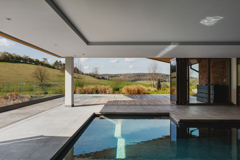 На фото: угловой бассейн среднего размера в доме в современном стиле с покрытием из бетонных плит с