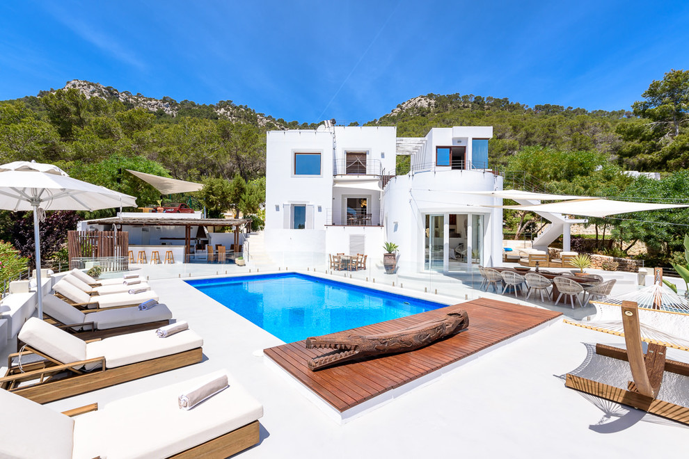 Aménagement d'une grande piscine méditerranéenne rectangle avec une terrasse en bois et une cour.