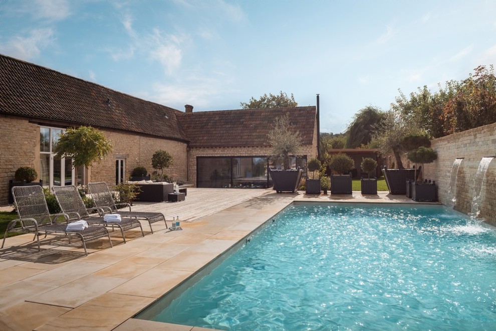 Ejemplo de piscina con fuente alargada clásica renovada de tamaño medio rectangular en patio trasero con suelo de hormigón estampado