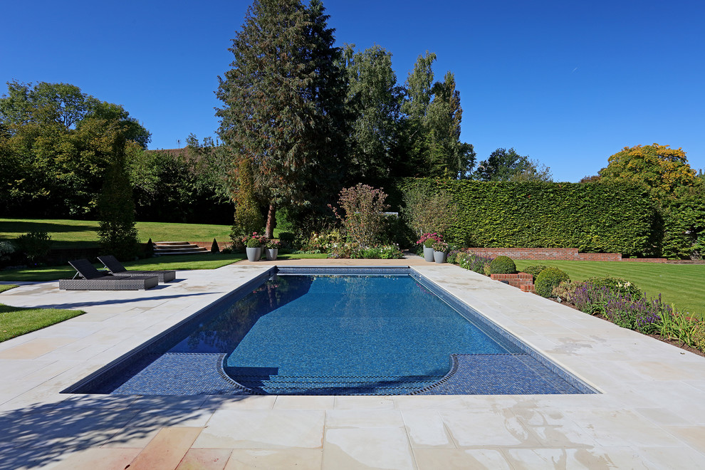 Example of a large classic backyard tile and rectangular pool design in Surrey