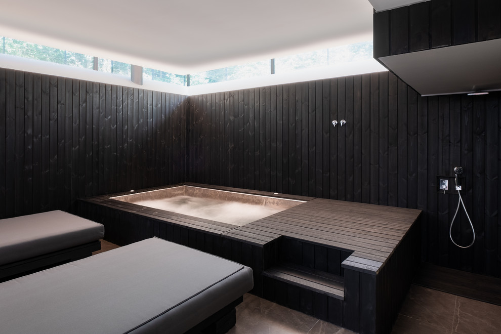 Réalisation d'une piscine intérieure hors-sol design rectangle avec un bain bouillonnant et une terrasse en bois.