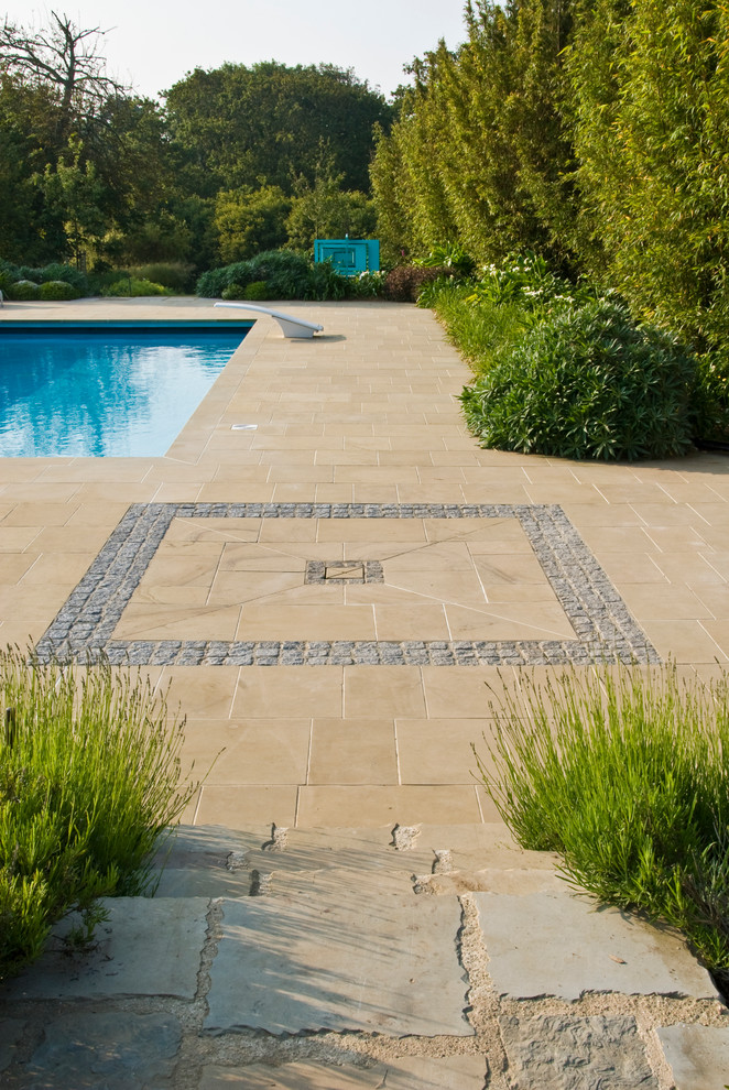 Large farmhouse back rectangular lengths swimming pool in Channel Islands with natural stone paving.