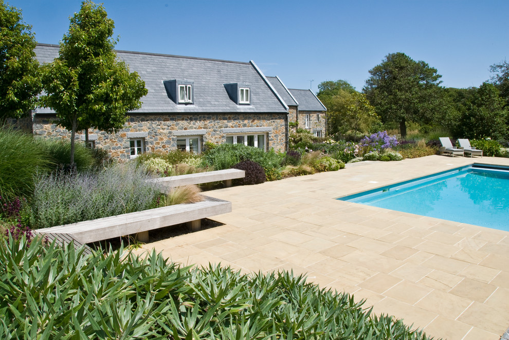 Inspiration for a large rural back rectangular lengths swimming pool in Channel Islands with natural stone paving.