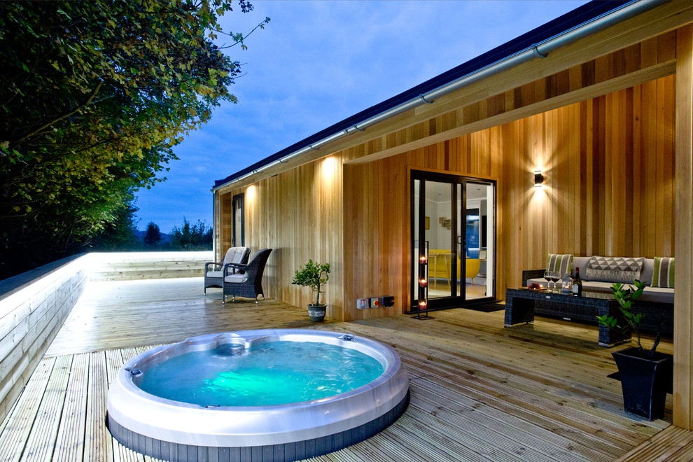 Cette photo montre une grande piscine sur toit bord de mer ronde avec un bain bouillonnant et une terrasse en bois.