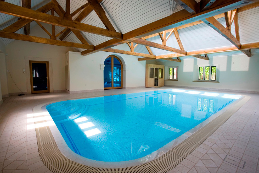 Imagen de piscina natural interior y rectangular con adoquines de piedra natural
