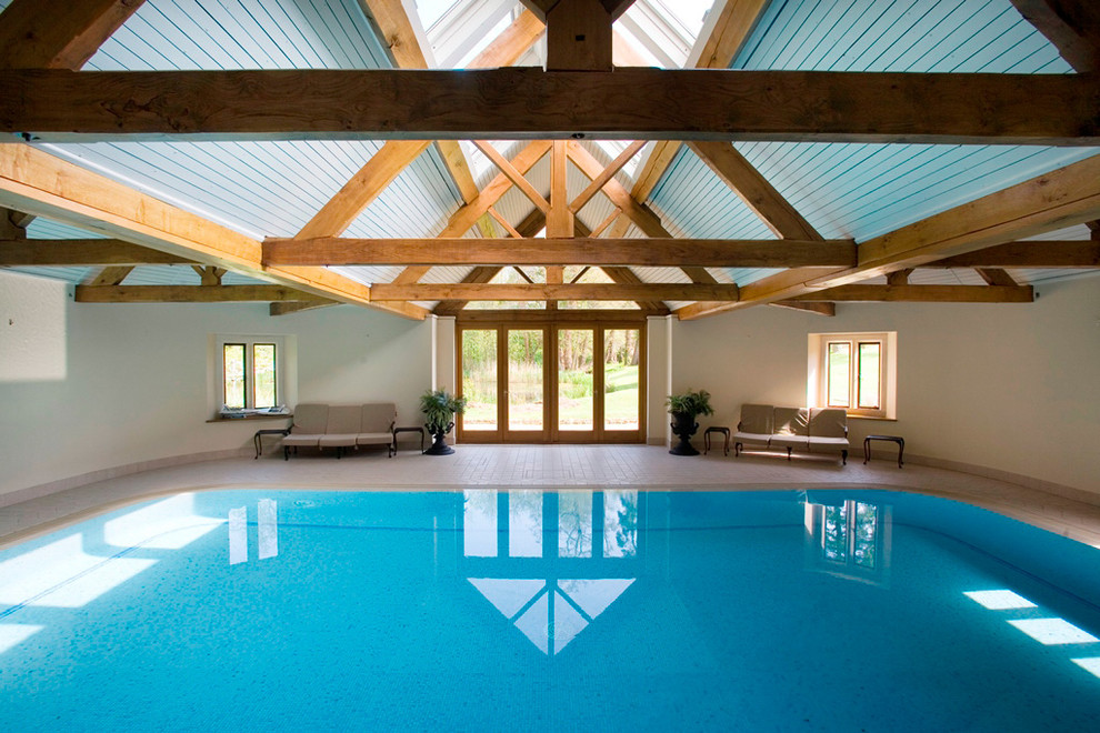Farmhouse indoor rectangular natural swimming pool in Sussex with natural stone paving.
