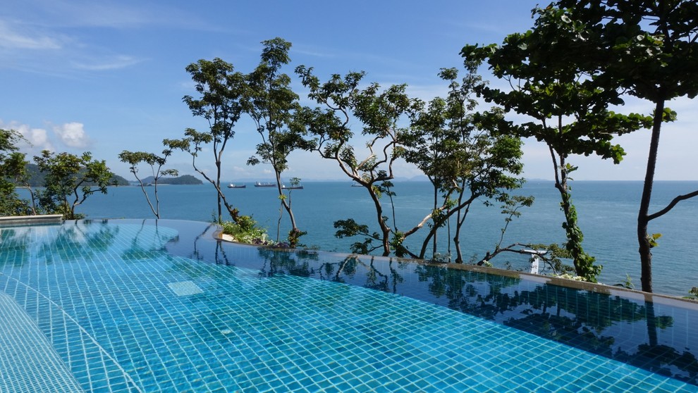 Ispirazione per un'ampia piscina a sfioro infinito mediterranea personalizzata dietro casa con piastrelle e fontane