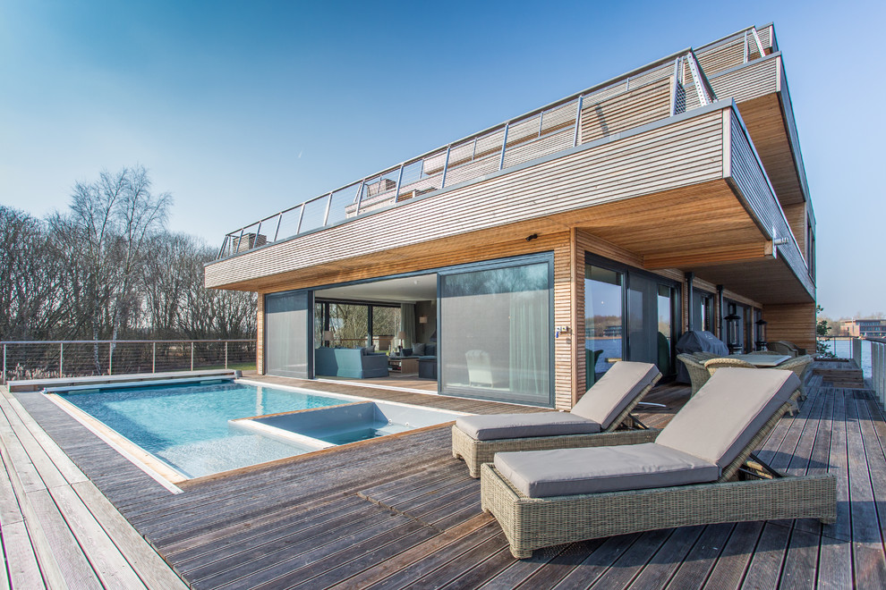 Modelo de casa de la piscina y piscina natural actual de tamaño medio en patio lateral con entablado