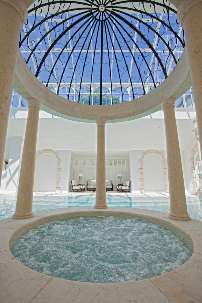 Inspiration for an expansive contemporary indoor round infinity hot tub with natural stone paving.