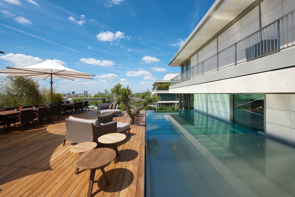 Cette image montre une piscine à débordement et arrière design rectangle avec une terrasse en bois.