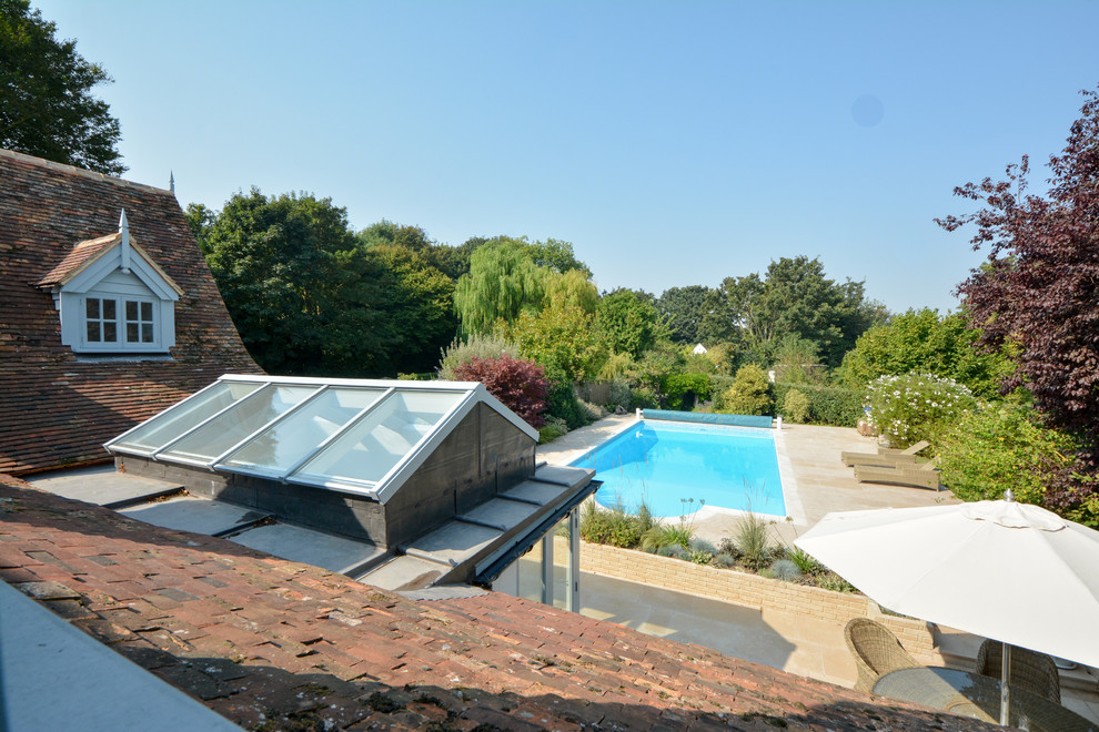 Photo of a large rural back rectangular lengths swimming pool in Kent with a pool house and natural stone paving.