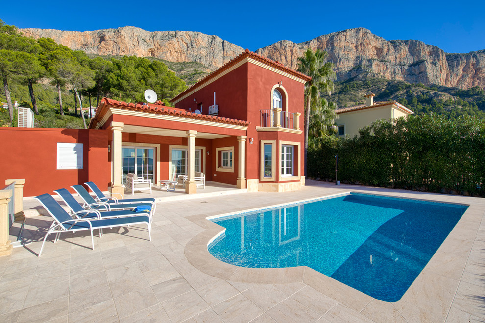 Modelo de piscina alargada mediterránea grande rectangular en patio trasero con adoquines de piedra natural