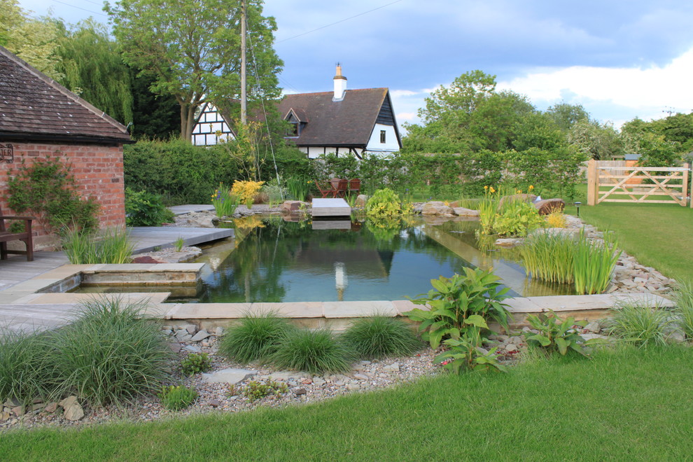 На фото: большой естественный, прямоугольный бассейн на заднем дворе в стиле кантри с фонтаном и покрытием из каменной брусчатки