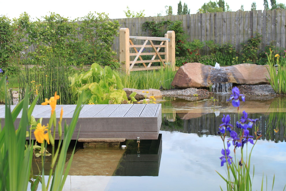 Modelo de piscina con fuente natural campestre grande rectangular en patio trasero con adoquines de piedra natural