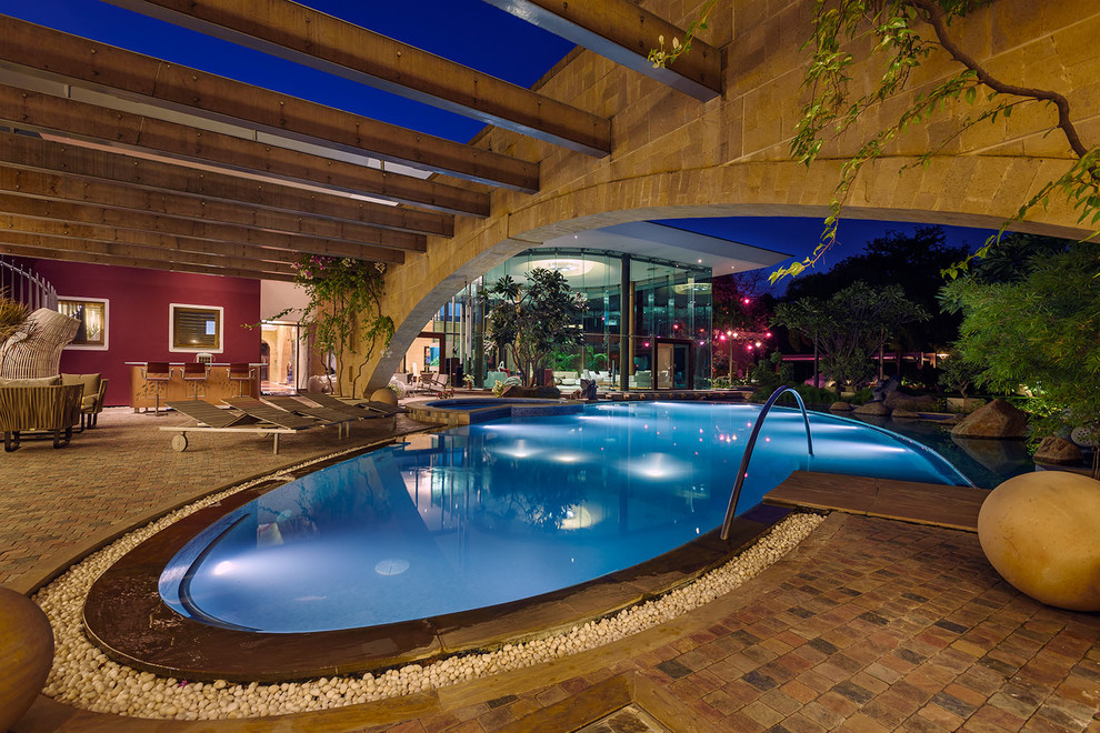Идея дизайна: большой бассейн произвольной формы на заднем дворе в стиле фьюжн с покрытием из плитки