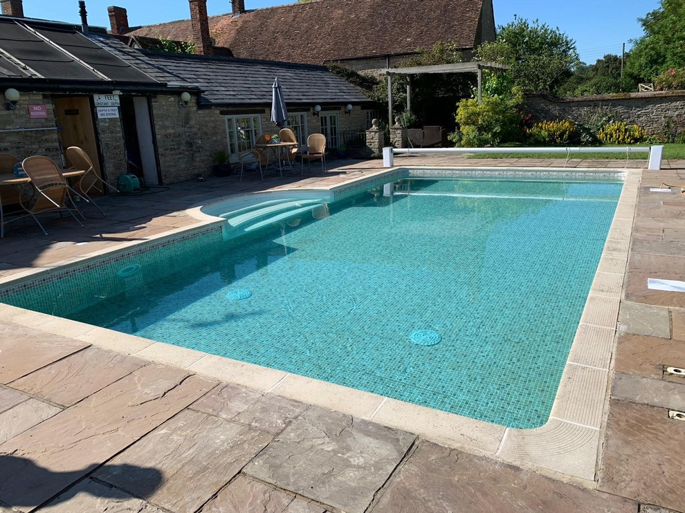 Diseño de piscina de estilo de casa de campo de tamaño medio rectangular en patio con adoquines de piedra natural
