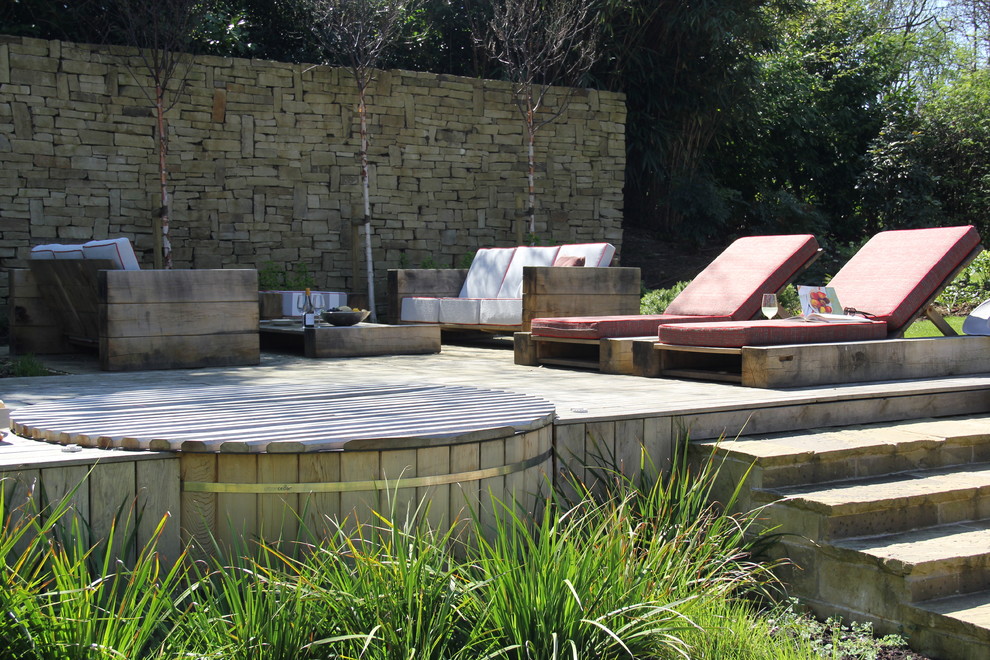 Réalisation d'une grande piscine arrière champêtre ronde avec un bain bouillonnant et une terrasse en bois.