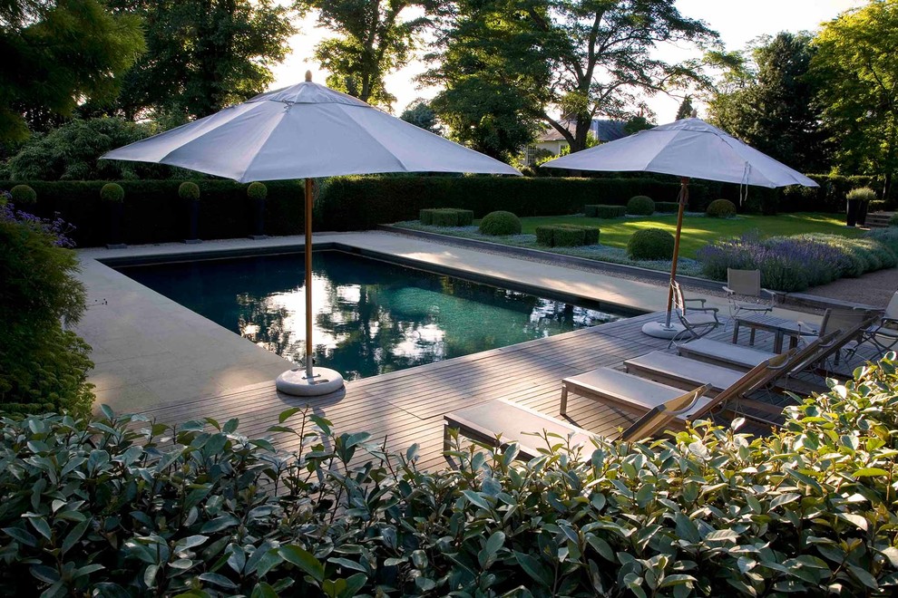 Ejemplo de piscina campestre de tamaño medio rectangular en patio trasero con adoquines de piedra natural